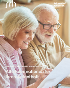 Ein älteres Paar sitzt zusammen und schaut auf ein Dokument, während sie lächeln. Text: "Alle Informationen für Ihren Aufenthalt."