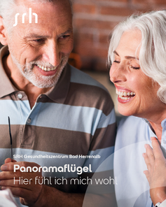 Älteres Paar lächelt und unterhält sich, während sie in einem gemütlichen Raum sitzen. Text: "Hier fühl ich mich wohl."