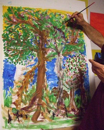 Ein Künstler malt mit einem Pinsel an einem großen, bunten Gemälde von Bäumen und einer lebhaften Landschaft.